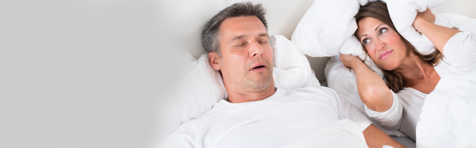 Snoring man with annoyed partner in bed